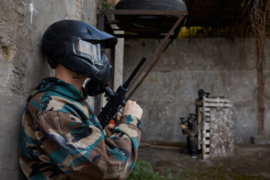 A portrait of a soldier standing against a wall, taking a stance, ready to shoot at his opponents