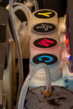 Refill color tanks on dtf textile printer. Printer ink supply system showing four primary color tanks.