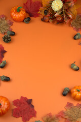 Obraz premium Autumn decorative elements like pumpkins, leaves, and acorns forming a frame on an orange background, perfect for copy space