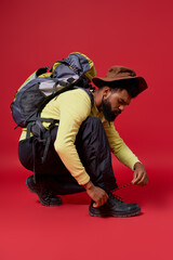 Fototapeta premium Stylish man prepares for adventure in warm attire against a vibrant red backdrop