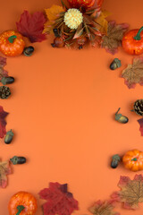 Fototapeta premium Fall decoration with pumpkins, leaves, and acorns framing a vibrant orange background, perfect for seasonal designs