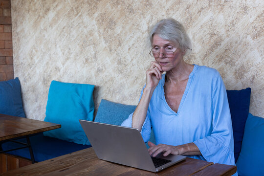 Pensive focused serious Senior Woman Using Laptop computer in Cafe