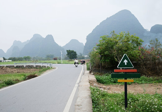 Motorcycle travels along road in a rural area with mountains