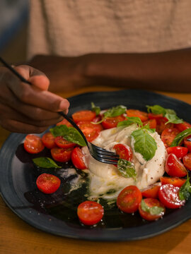 Woman enjoying fresh burrata salad at home 