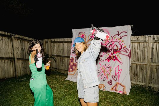 UGC Two friends posing with spray paint at graffiti backyard party
