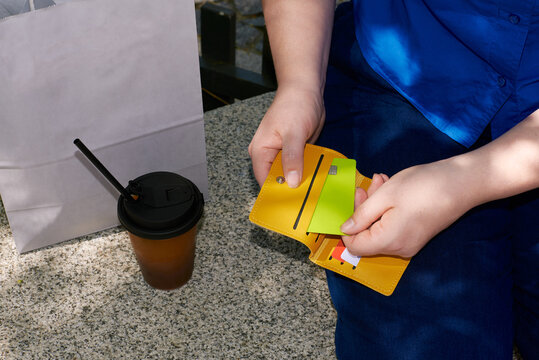 A person sits on the street and takes a bank card out of his wallet.