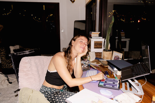 Woman smiling at messy desk during late night work from home