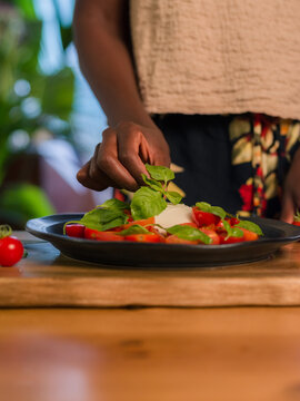 Woman decorating salad with basil leaved 