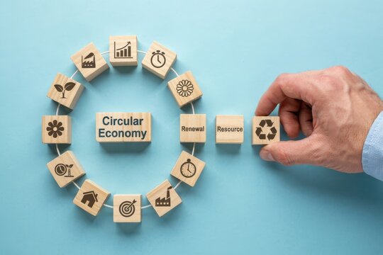 Circular economy concept with wooden blocks and icons forming a circle, a hand placing a recycling block