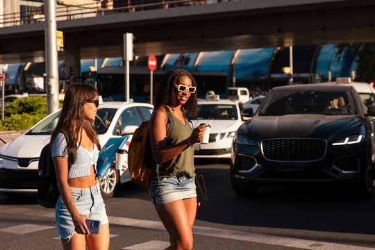 Teenage girls crossing street with backpacks and school items