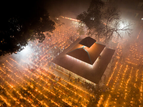 Narayanganj, Bangladesh - 09 November 2024: Aerial view of a temple illuminated by thousands of oil lamps during a religious festival, with devotees gathered in the courtyard.