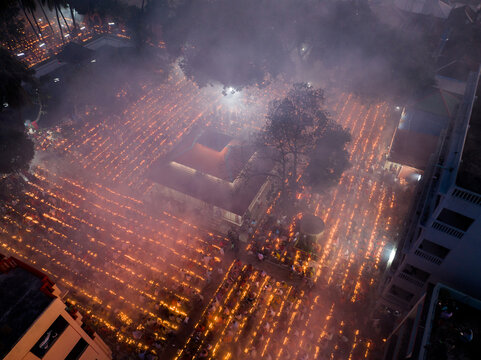 Narayanganj, Bangladesh - 09 November 2024: Aerial view of devotees holding lit candles in rows during the Kartik Brata festival, creating a glowing grid pattern in the night.