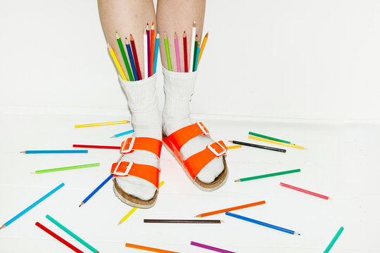 Person wearing fashion style sandals & sock full of colour art pencils