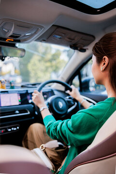 Woman driving modern car through city