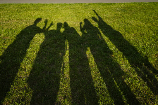 Shadows of people waving on green grass