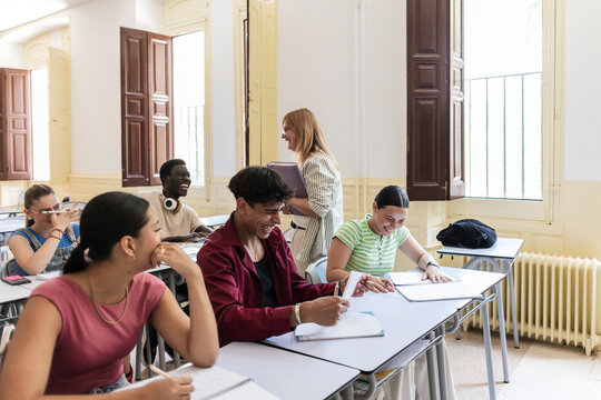 Diverse students and teacher laughing enjoying class activity