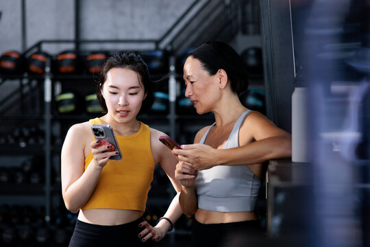 Women at the gym looking at phones together.