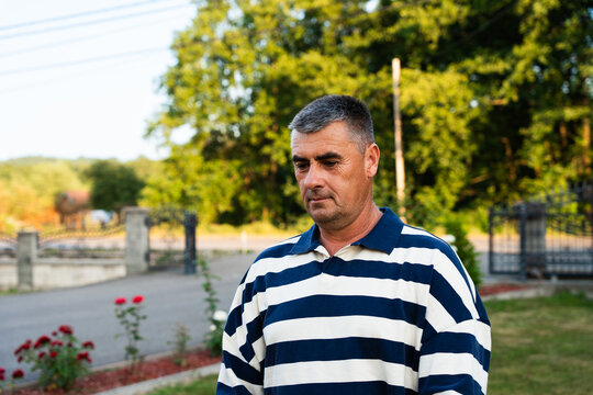 Man standing outdoors in a residential garden at sunset