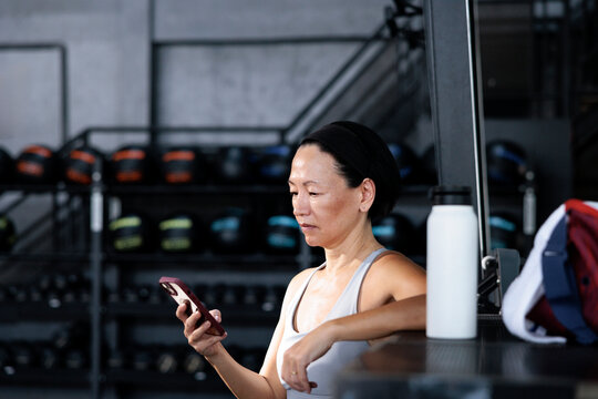 Woman checks phone during gym break.