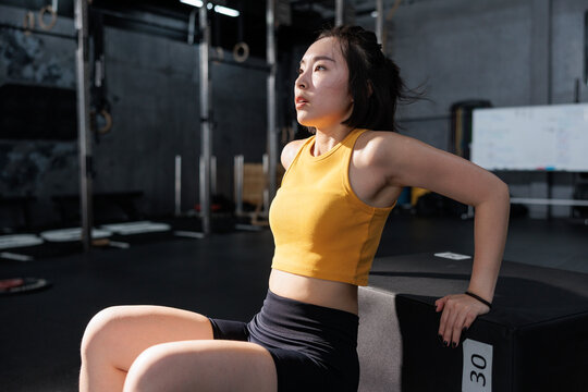 A focused young woman performing tricep dips in a gym.