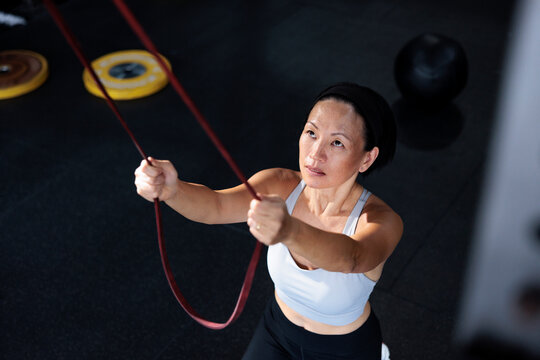 Woman exercising with resistance band in gym.