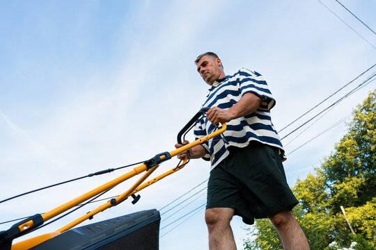 Low angle view of man mowing lawn in residential garden