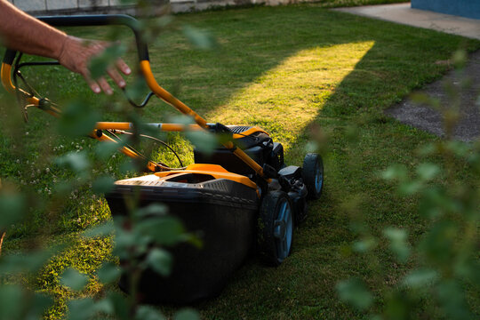 Close up of lawn mower collecting grass during evening yard work