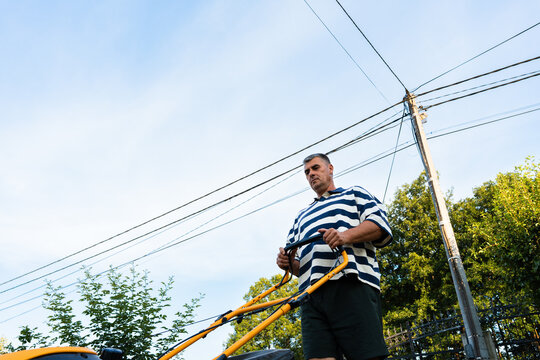 Low angle view of man mowing lawn in residential garden