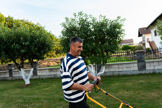 Man mowing grass in a residential garden during summer
