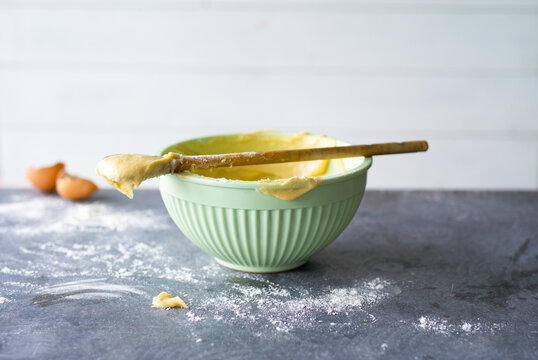 Mixing bowl with raw cake dough and wooden spoon on a table