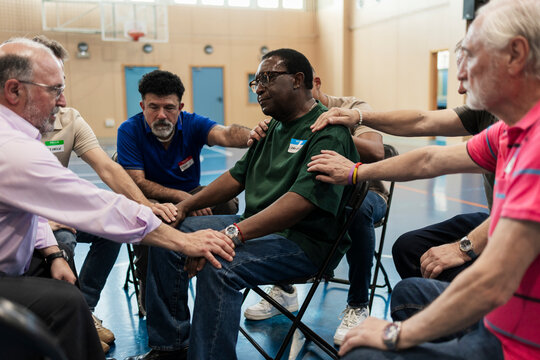 Group of diverse men supporting one another in a therapeutic circle