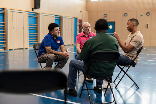 Diverse men involved in support group discussion sitting in circle