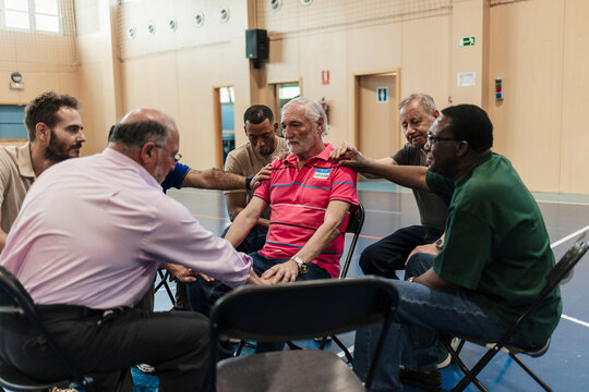 Diverse men offering support during group prayer meeting