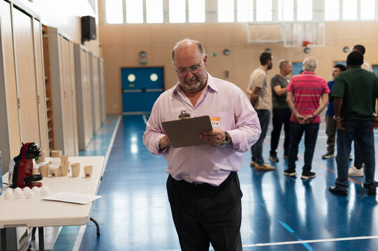 Volunteer man checking checklist managing event indoors