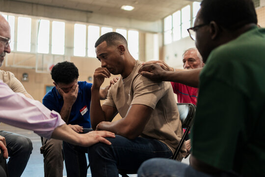 Diverse men supporting each stressed member in group therapy