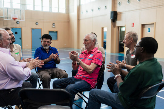 Diverse men clapping hands at support group meeting