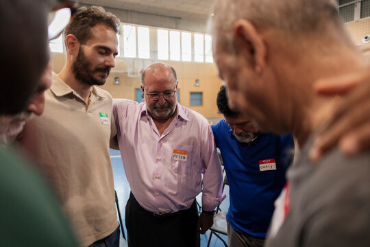 Diverse men standing together forming supportive prayer circle