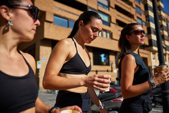 Women walking on a city street while enjoying drinks in the morn
