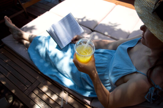 Anonymous middle-age woman with book on a sun lounger.