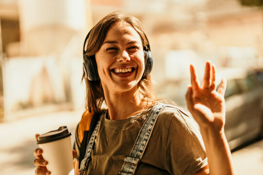 Young woman enjoying music and coffee on city street