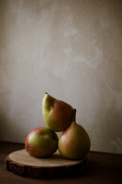 Three Pears Arranged on a Wooden Slice in Soft Light