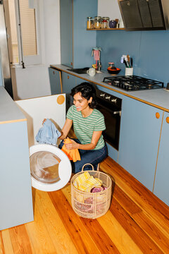 Woman doing laundry in modern home kitchen ugc
