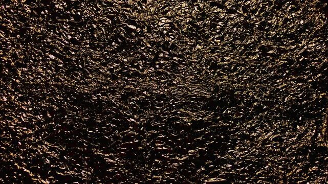 crumpled gold foil texture glittering against deep shadow for luxury branding web design and festive backdrops