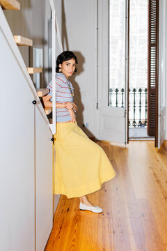 Woman leaning on staircase in modern apartment ugc