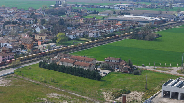 Pontenure, Italy - 30 March 2026: Aerial view of the Xella Italia S.r.l. facility and the town of Pontenure, with a freight train passing through the green landscape.