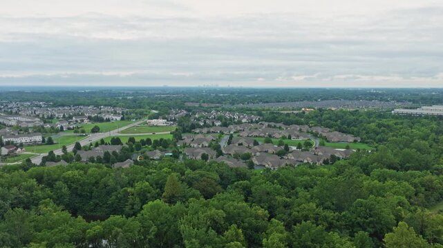 Drone aerial above city of Hilliard, Ohio suburban landscape as a suburb outside Columbus, OH with townhomes, residential units, duplex homes, houses, and rental buildings in middle class neighborhood