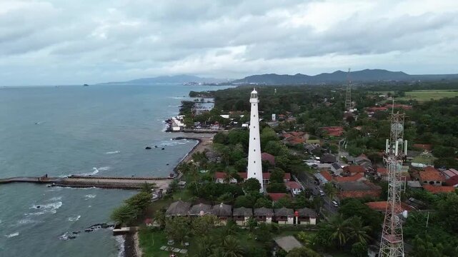 Cinematic drone footage capturing Mercusuar Titik Nol (Zero Point Lighthouse) in Anyer, Banten, Indonesia. The aerial view showcases the iconic lighthouse, surrounding coastline, the Sunda Sreet.