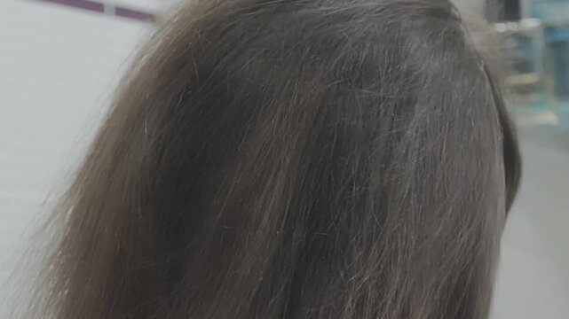 Woman with brown, brittle, and split hair is massaging a conditioning oil into her scalp and strands for deep nourishment and therapy