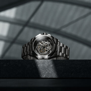 Luxury skeleton watch with metal bracelet on dark stone pedestal for premium advertising.