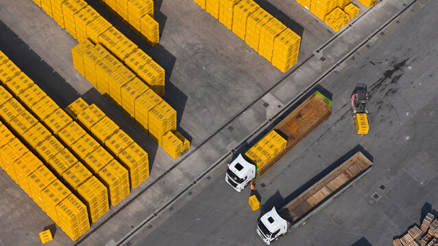 Pontenure, Italy - 30 March 2026: Aerial view of the Ytong factory yard with stacks of yellow aerated concrete blocks, trucks, and a forklift operating in the industrial space.